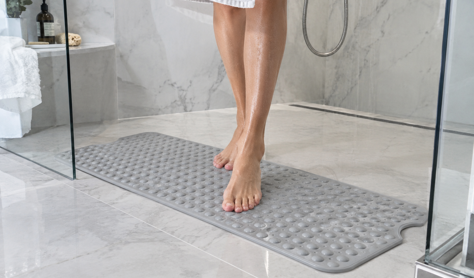 Extra-long non-slip bath mat with suction cups and drainage holes laid along the floor of a bathtub